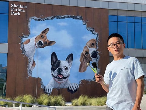 Created by artist Jack Lee, the mural is featured on a facade at the Sheikha Fatima Park, and shows three dogs peering through a hole.