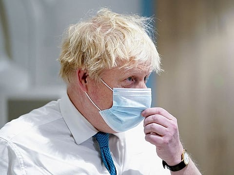 British Prime Minister Boris Johnson adjusts his mask during his visit to the Kent Oncology Centre at Maidstone Hospital in Kent, Britain, February 7, 2022.