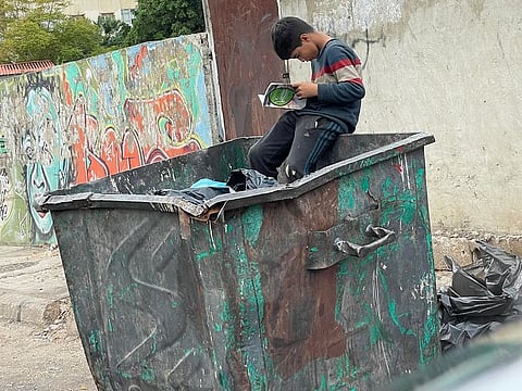 Hussein found a book to read in the garbage bin while collecting trash to support his family