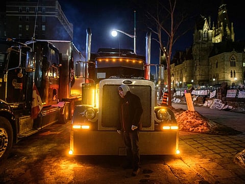 A truck driver listens to the engine of his truck during a protest over pandemic health rules and the Trudeau government, outside the parliament of Canada in Ottawa on February 14, 2022.