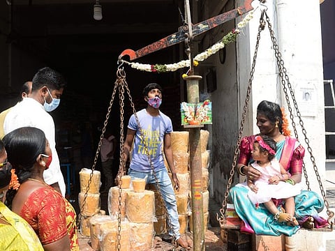A Hindu devotee along with her daughter sits on a scale to buy jaggery in a quantity equal to her weight to worship tribal deities ahead of the Medaram Jatara festival, at a wholesale shop in Hyderabad.