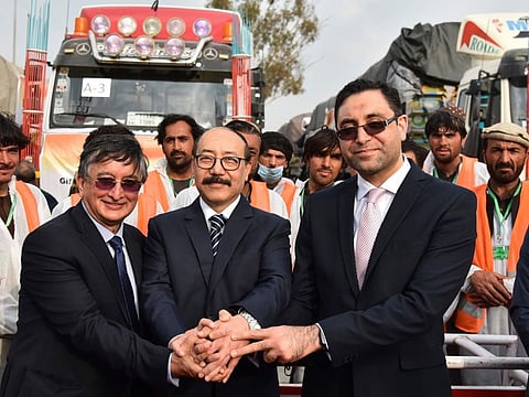 India’s foreign secretary Harsh Vardhan Shringla, centre, and Afghanistan’s ambassador to India Farid Mamundzay, right, join hands as they pose before the trucks carrying wheat from India passed through the Attari-Wagah border between India and Pakistan, near Amritsar, India, on February 22, 2022.