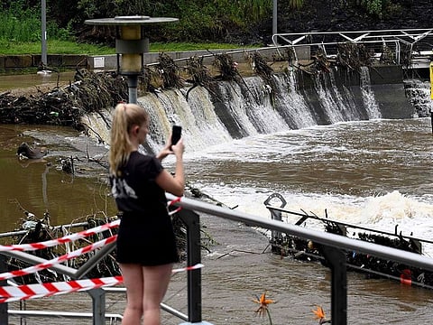 A woman takes pictures of the overflowing Parramatta river at the ferry wharf in Sydney on February 23, 2022, after heavy rain lashed eastern Australia, causing flash flooding and a string of emergency warnings up and down the Pacific coast.