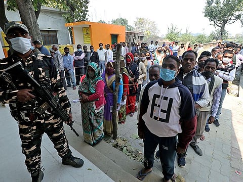 Voters wait in queues to cast their votes for the fourth phase of Uttar Pradesh Assembly elections, at a polling booth, in Lucknow on Wednesday