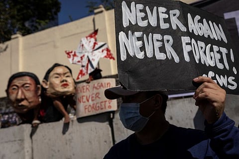 A Filipino raises a placard during a rally marking the anniversary of the 1986's People Power Revolution that overthrew the late dictator Ferdinand Marcos, near the EDSA People Power monument in Quezon City, Metro Manila, Philippines, February 25, 2022.