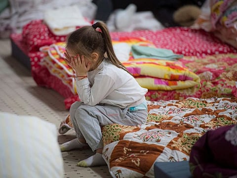 A child refugee who fled the conflict from neighbouring Ukraine covers her face in the event hall of a hotel offering shelter in Siret, Romania, Saturday, Feb. 26, 2022. Romania, which shares around 600 kilometres (372 miles) of borders with Ukraine to the north, is seeing an influx of refugees from the country as many flee Russia’s attacks.(AP Photo/Alexandru Dobre)