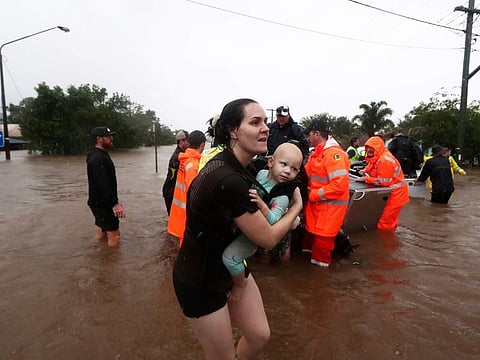 A woman carries a baby as people use small boats to travel through flood water in Lismore, Australia, Monday, Feb. 28, 2022.
