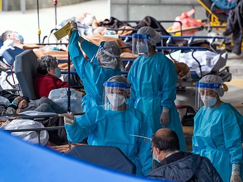 Healthcare workers wearing personal protective equipment (PPE) attend to patients at a temporary triage area at the Caritas Medical Center hospital in Hong Kong on Monday, Feb. 28, 2022.