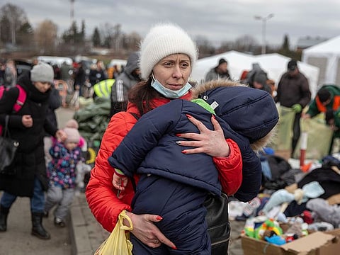 A woman carries her child as she arrives at the Medyka border crossing after fleeing from the Ukraine, in Poland, Monday, Feb. 28, 2022