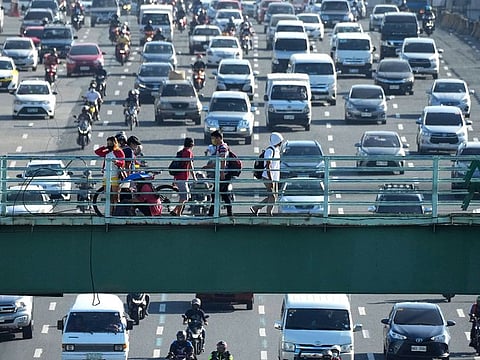 People walk on an overpass as traffic builds up as health authorities downgraded the capital Manila to Alert Level 1, the lowest rung of a five-step pandemic alert system on Tuesday, March 1, 2022. Photo taken in Quezon city, Philippines.