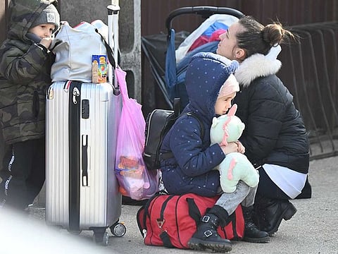 A Ukrainian woman and two children wait next to their luggage in the village of Tiszabecs, Hungary, close to the Hungarian-Ukrainian border