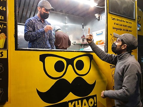 People communicate using sign language outside Pakistan's first mobile restaurant, staffed entirely by deaf workers, in Islamabad.
