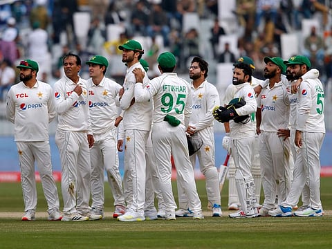 Pakistan players wait for third umpire decision about the dismissal of Australia's Usman Khawaja during the 3rd day of the first cricket Test at the Pindi Stadium, in Rawalpindi, Pakistan.