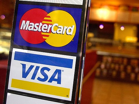 This April 22, 2005, file photo, shows logos for MasterCard and Visa credit cards at the entrance of a New York coffee shop. Mastercard and Visa are suspending their operations in Russia, the companies said Saturday, March 5, 2022, in the latest blow to the country's financial system
