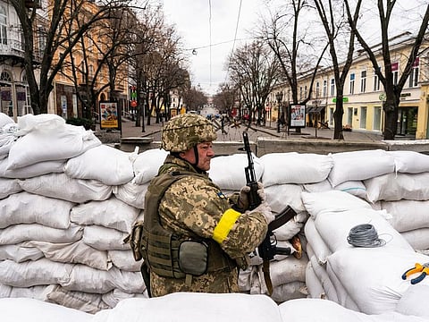 A Ukrainian soldier stands guard among the sandbags in downtown Odessa on Saturday