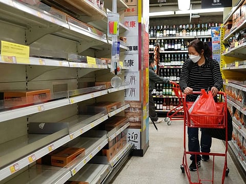 A woman walks next to empty shelves for noodles after residents concerned with possible shortages stock up on food, at a supermarket Hong Kong on March 6, 2022.