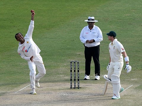 Pakistan's Nauman Ali (left) bowls next to Australia's Steven Smith during the fourth day of the first Test cricket match between Pakistan and Australia at the Rawalpindi Cricket Stadium in Rawalpindi.