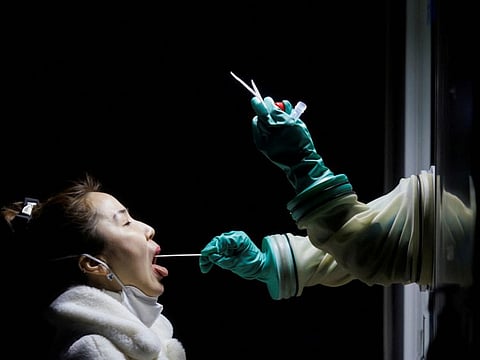 A woman receives a throat swab test at a street booth as the coronavirus disease (COVID-19) pandemic continues in Beijing, China, January 17, 2022.