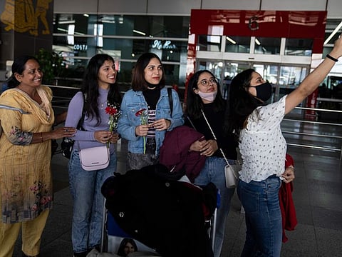 Indian students studying in Ukraine who were evacuated from Sumy stand for a selfie with family members upon arrival at the Indira Gandhi International Airport in New Delhi, on March 11, 2022.