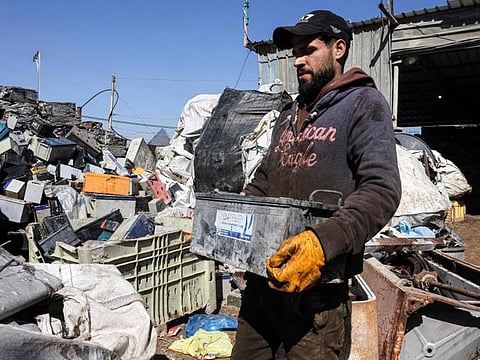 A Palestinian man picks discarded batteries to resell for recycling in Khan Yunis in the southern Gaza Strip, on February 14, 2022.