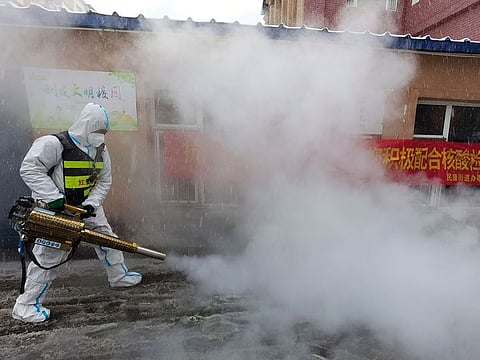 A volunteer disinfects the area as it snows during the COVID-19 lockdown in Changchun in northeast China's Jilin province.