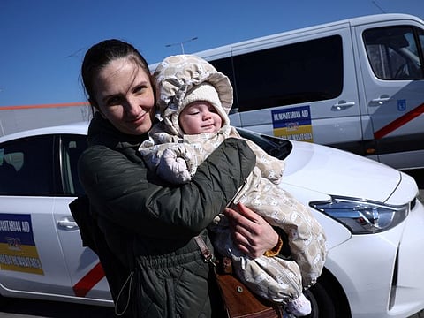 A Ukrainian woman called Olga, 38, holds her 6-month-old daughter Vera near Spanish taxis, in front of the reception centre for refugees in Nadarzyn, Poland, on March 14, 2022.