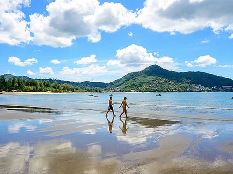 Tourists walk on a beach on the Thai island of Phuket.