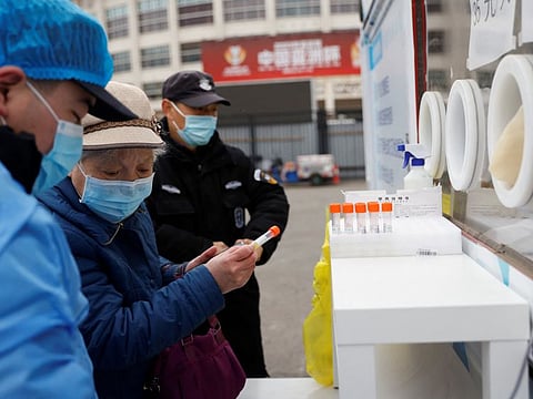 A woman holds a sample tube before getting tested for COVID-19 at a mobile nucleic acid testing site on a street in Beijing on March 17, 2022.
