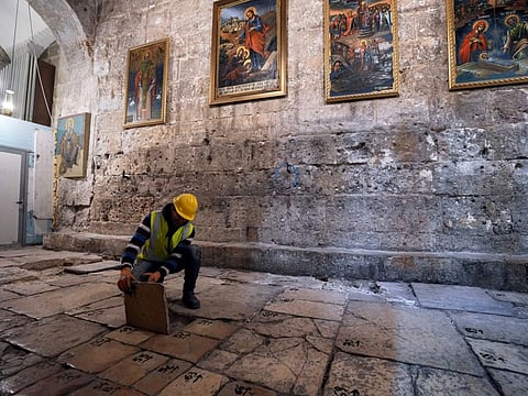 A member of the restoration team removes a stone from the floor of the Church of the Holy Sepulchre in the Old City of Jerusalem on March 17, 2022.
