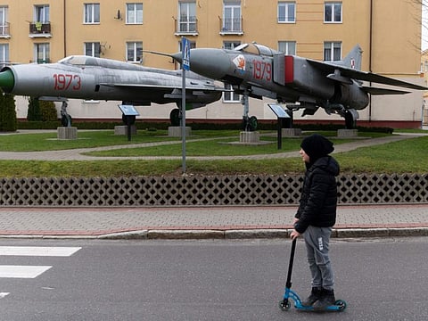 A boy passes by a monument, dedicated to the memory of the fallen pilots of the 28 Slupsk Fighter Aviation Regiment, located nearby the entrance to the military base in Redzikowo, Poland, on February 24, 2022.