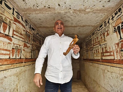 Mostafa Waziri, Secretary General of the Supreme Council of Antiquities, displays a statue at a tomb decorated with hieroglyphic inscriptions and images of sacred animals and after-life items used by ancient Egyptians, at a recently discovered tomb near the famed Step Pyramid, in Saqqara, south of Cairo, on March 19, 2022.