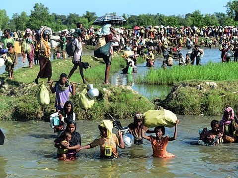 In this file photo taken on October 16, 2017, Rohingya refugees walk through a shallow canal after crossing the Naf River as they flee violence in Myanmar to reach Bangladesh in Palongkhali near Ukhia.