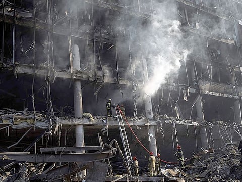 Firefighters try to extinguish a fire amid the destruction caused after shelling of a shopping center, in Kyiv.