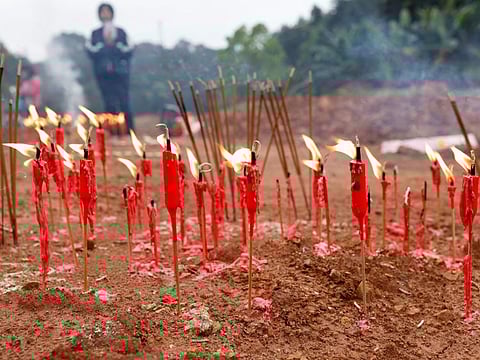 People burn candles and incense sticks during a Buddhist ceremony in honour of the victims in a field close to the entrance of Simen village, near the site where a China Eastern Airlines Boeing 737-800 plane flying from Kunming to Guangzhou crashed, in Wuzhou, Guangxi Zhuang Autonomous Region, on March 22, 2022.
