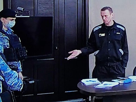 Russian opposition leader Alexei Navalny, right, gestures via a video link provided by the Russian Federal Penitentiary Service, as he speaks with Penitentiary Service officers during a court session in Pokrov, Vladimir region, about 100 kilometers (62 miles) east of Moscow, on March 22, 2022.