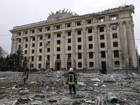 A member of the Ukrainian Emergency Service looks at the City Hall building in the central square following shelling in Kharkiv, Ukraine, Tuesday, March 1, 2022.
