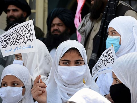 School girls hold Taliban flags during a ceremony to mark the start of the academic year at a primary school in Kandahar on March 24, 2022.