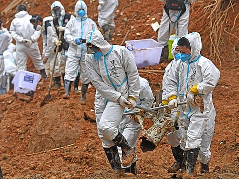 Searchers carry a piece of plane wreckage at the site of Monday's plane crash in Tengxian County, southern China's Guangxi Zhuang Autonomous Region.
