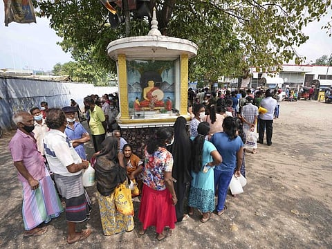 Sri Lankans wait in queue to buy kerosene oil at a fuel pump in Colombo.