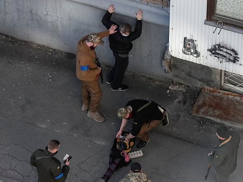 Members of the Ukrainian Territorial Defence Forces check a man as they patrol during a long curfew in Kyiv.