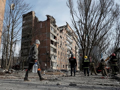 A woman carries a bottle of water as emergency specialists work at a residential building damaged by shelling during Ukraine-Russia conflict in the separatist-controlled city of Donetsk on March 30, 2022.
