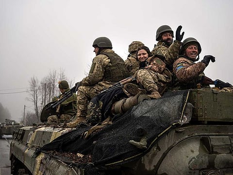 Ukrainian soldiers wave to reporters during a military sweep to search for possible remnants of Russian troops after their withdrawal from villages in the outskirts of Kyiv, Ukraine, Friday, April 1, 2022.