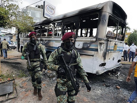 Sri Lankan army commandos walk past a damaged bus after it was set on fire by demonstrators at the top of the road to Sri Lankan President Gotabaya Rajapaksa's residence during a protest against him, as many parts of the crisis-hit country face up to 13 hours without electricity due to a shortage of foreign currency to import fuel, in Colombo, Sri Lanka April 1, 2022.