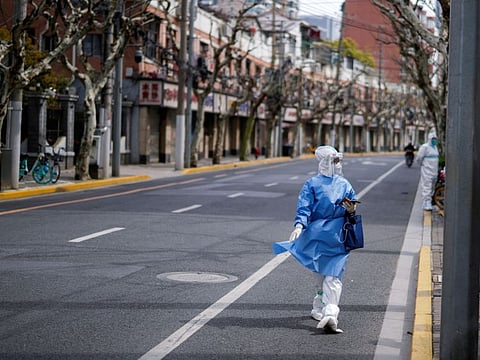 A worker in a protective suit keeps watch on a street, as the second stage of a two-stage lockdown to curb the spread of the coronavirus disease (COVID-19) begins in Shanghai, China April 1, 2022.