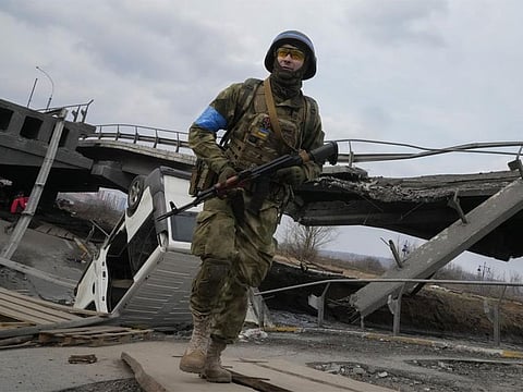 A Ukrainian soldier crosses the destroyed bridge in Irpin close to Kyiv, Ukraine, Thursday, March 31, 2022. The more than month-old war has killed thousands and driven more than 10 million Ukrainians from their homes including almost 4 million from their country.
