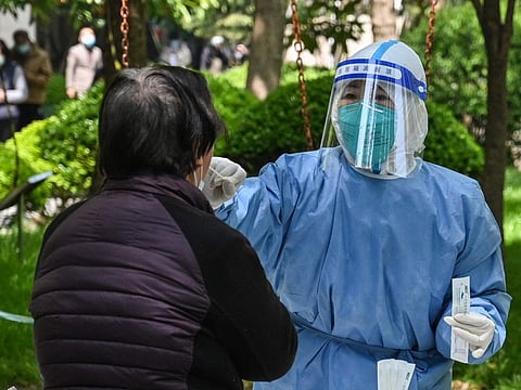 A health worker conducts a swab test for the Covid-19 coronavirus at a residential compound during the second stage of a pandemic lockdown in Jing' an district in Shanghai on April 6, 2022.