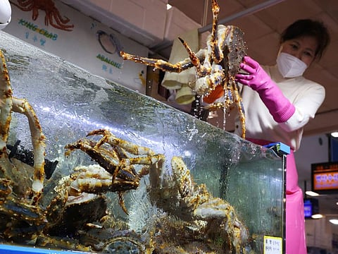 Kim Mi-kyeong, a shopkeeper, shows a king crab imported from Russia to a customer at Noryangjin Fisheries Wholesale Market in Seoul, South Korea, April 8, 2022.