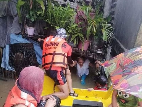 A rescuer assists a woman onto a rescue boat, after the tropical storm Megi hit, in Capiz, Philippines.