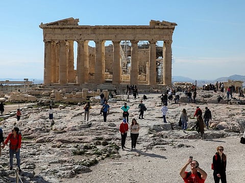 People visit the ancient Parthenon Temple atop the Acropolis hill archaeological site in Athens, Greece, in a file photo.