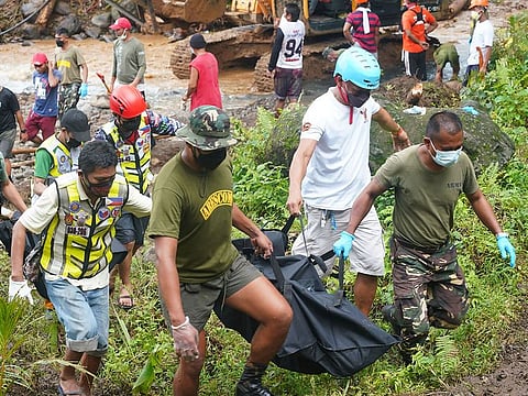 Rescue workers carry body bags containing the retrieved bodies of victims of a landslide that slammed the village of Bunga in Baybay town, Leyte province on April 13, 2022, days after heavy rains inundated the town brought about by Tropiical storm Megi.